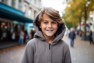 Portrait of a smiling little boy in hoodie on the street