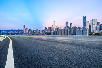 Asphalt road and urban skyline with modern buildings at dusk in Chongqing