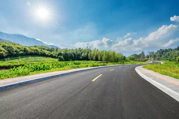 Schilderijen op glas Country road and green forest with mountain natural landscape on a sunny day © ABCDstock