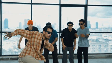 Multicultural hipster group looking at camera while perform break dancing at building with sky scrapper or city view. Street dancer team looking at dancer performance. Outdoor sport 2024. Endeavor.