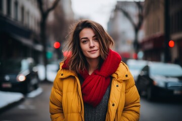Portrait of a beautiful young woman in yellow coat and red scarf on the street.