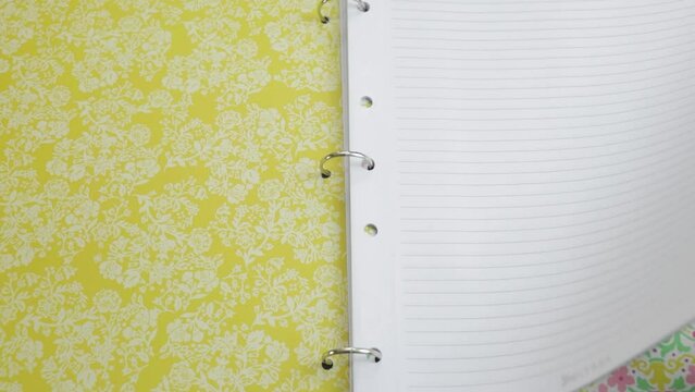 Turning ornate papers on steel ring page binder in arch lever file.