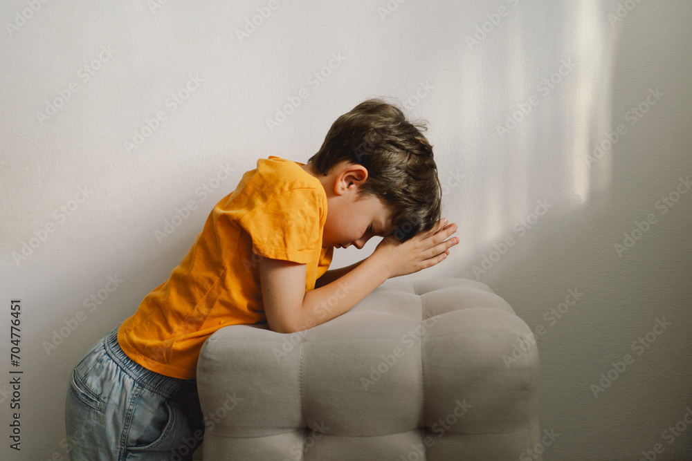 Wall mural a boy in an orange t-shirt prays at home. reading the holy bible. concept for faith, spirituality an