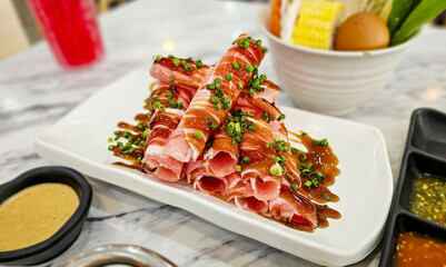 Close-up raw fresh pork slide in white plate on table, Fresh raw pork slides on plate served for Sukiyaki and Shabu. The streaky pork for shabu hotpot.