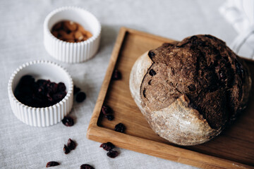 A loaf of homemade rye bread with cranberries on a wooden tray on the dining room table. Farm products, fresh baked goods