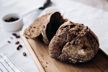 A loaf of homemade rye bread with cranberries on a wooden tray on the dining room table. Farm products, fresh baked goods