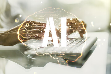 Double exposure of creative artificial Intelligence symbol with hands typing on laptop on...