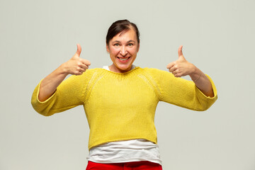 Middle aged woman smiling showing class sign on gray background