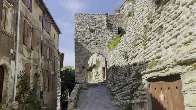 Small street in a historic village with old stone wall rest with archway to drive through in the sunshine of France