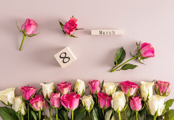 Beautiful festive background for International Women's Day on the eighth of March with delicate white and pink roses and a wooden calendar. border.