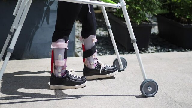  child with walking frame and knee orthosis outdoor 