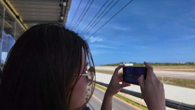 A woman stands and takes photos of a plane on the runway next to the airport as it slowly passes by.
People stand on the airport rice terrace to watch the planes.
runway background.