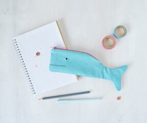 Blue whale pencil case, notes, pens and washi tapes on desk	