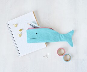 Blue whale pencil case, notes, pens, golden clips and washi tapes on desk	
