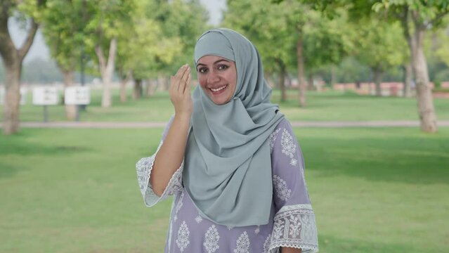 Happy Muslim woman doing Adaab in park