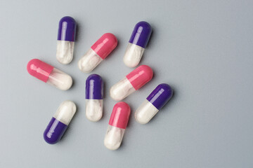 close-up of blue and pink dry powder inhalation capsules, contain dry powder form of the medication released and inhaled into the lungs isolated on neutral grey background with copy space
