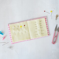 Simple handmade needle book, pins, thread clipper and clips on white