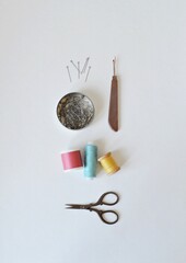 Spool threads, pins in round jar, seam ripper and small scissors on white background	