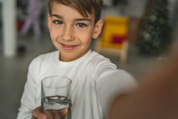 One boy caucasian kid stand at home hold glass of water thirsty drink