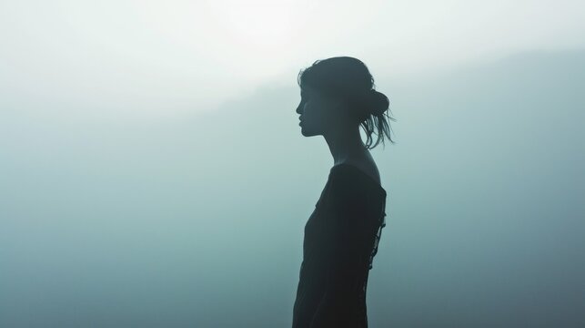  a woman standing in a foggy area with her head turned to the side and her hair blowing in the wind.