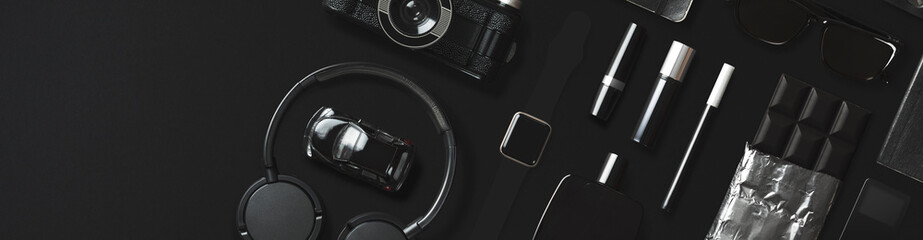 Black fashion and technology items flat lay on black background