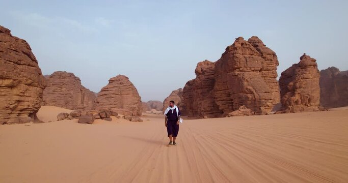 Male Tourist Walking Near Rock Formations At Sunset In Tassili n'Ajjer National Park In Algeria. wide shot