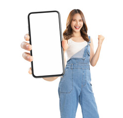 Cheerful young Asian woman holding smartphone with fists clenched celebrating victory expressing...
