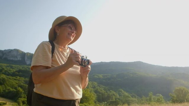 Senior woman photographer taking photos in the mountains on a sunny day