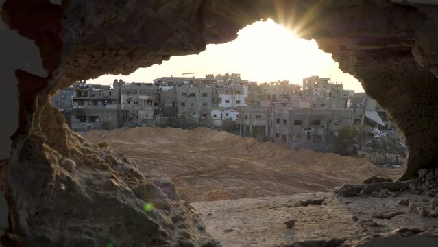 Looking out through remains of a wall  towards destroyed city blocks in Gaza