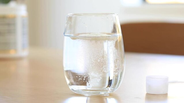 Slow video. White collagen powder dissolves in a transparent glass close-up. 