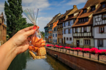 Woman s hand holding a bag of artisanal cookies with half timbered houses above channels of the...