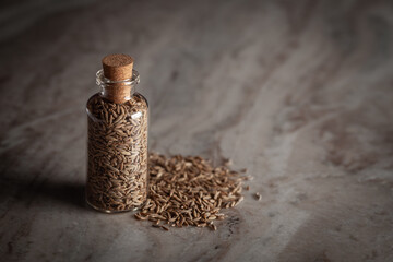 A small glass bottle filled with organic cumin seed (Cuminum cyminum) or jeera is placed on a...