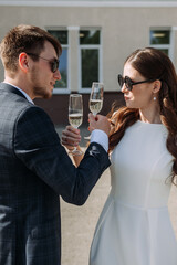 A man and a woman standing outdoors, both holding wine glasses. 5164