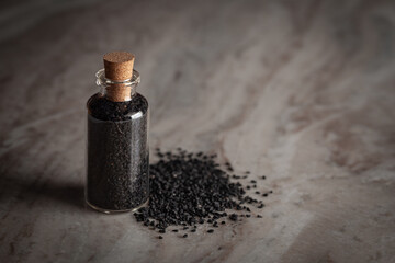 A small glass bottle filled with organic black cumin  (Nigella sativa) or kalonji is placed on a...