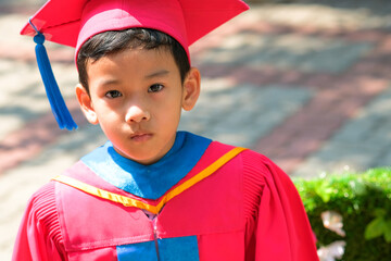 Close-up image portrait of a Asian boy on graduating from kindergarten, he is wearing graduation...