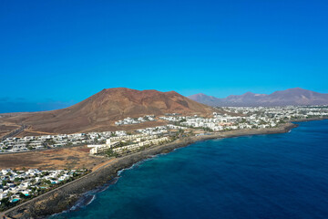 Playa Blanca coastline. Aerial drone panoramic view with Red volcano in the Background. Tourism and vacation concept. Flamingo beach  Lanzarote, Canary Islands, Spain.