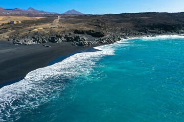 Fototapeta na wymiar Drone panoramic view of Playa del Janubio in Lanzarote with the volcanic landscape in the background with turquoise sea and big waves. Nature and tourism. Canary Islands, Spain.