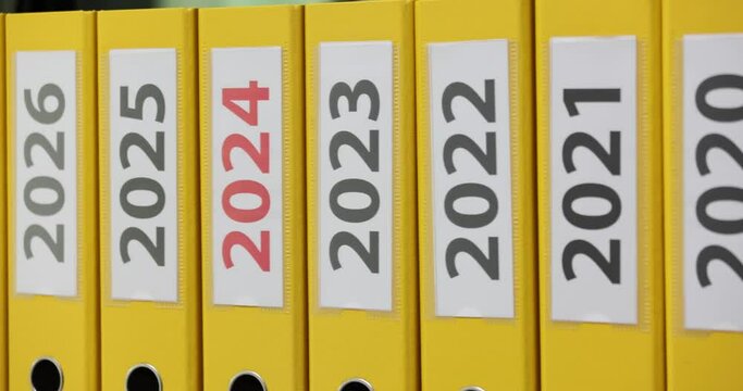 Set of yellow ring bingers on shelf with years labels