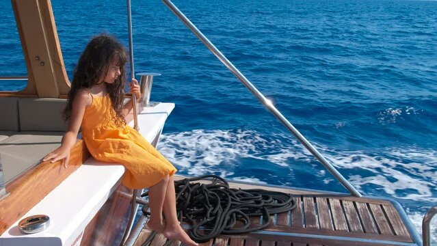 A child crunches on a ship at sea. A lonely little girl sits at the stern of the ship.