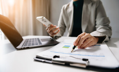 business documents on office desk with laptop and smart phone and graph business diagram and man working in office.