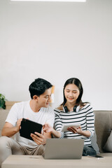 Obraz premium Female discussing new project with male colleague. Young woman talking with young Asian man with financial on sofa