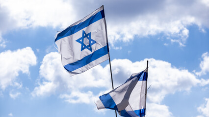 Two israeli flags waving on blue sky background - 704852042