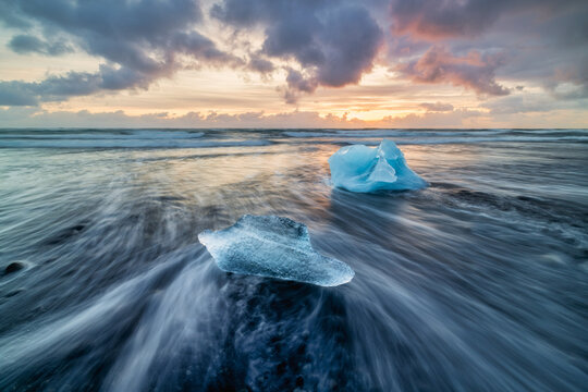 Blue ice fragments in the sea on black sand Diamond beach in Iceland