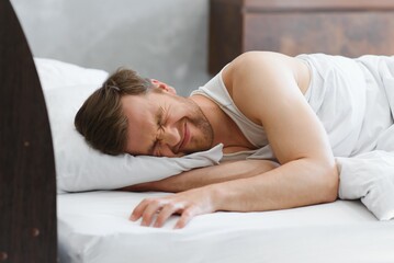 Sleepy bachelor on the bed ready to wake up or go to sleep. Study hard or burned out concept.