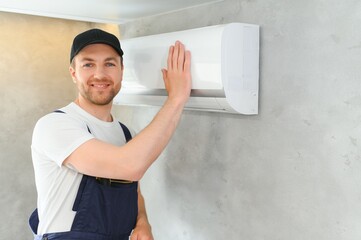 Happy Male Technician Repairing Air Conditioner.