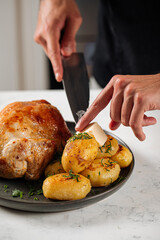 Chef preparing appetizing baked whole chicken with potatoes