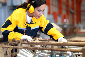Latin engineer in safety uniform work in heavy steel engineering factory. Young female hispanic...