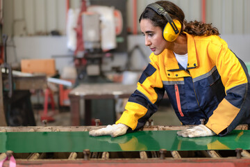 Latin engineer in safety uniform work in heavy steel engineering factory. Young female hispanic...