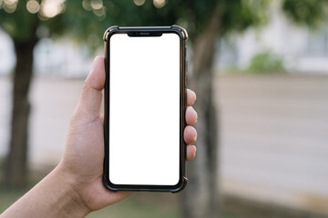 Mockup image of hand holding white mobile phone with blank white green nature background.