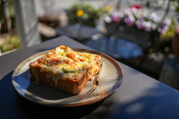 カフェのテラス席で食べるピザトースト